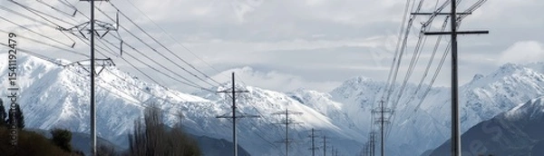 Fototapeta Power lines stretching across snowcapped mountains