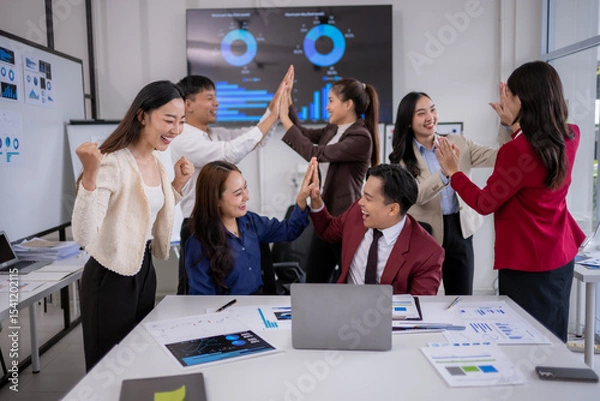 Fototapeta Enthusiastic business team celebrating successful project with high fives in office