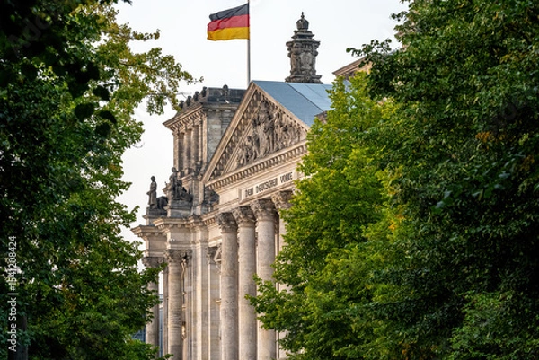 Fototapeta The entrance portal to the Reichstag in Berlin seen through some trees