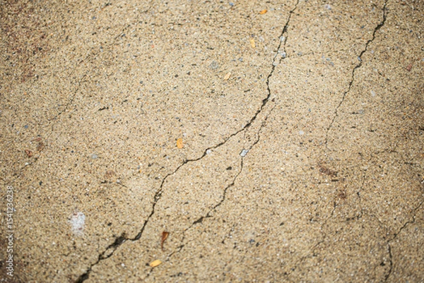 Fototapeta Close up shot of concrete floor with oblique cracking, in light brown color, retro style