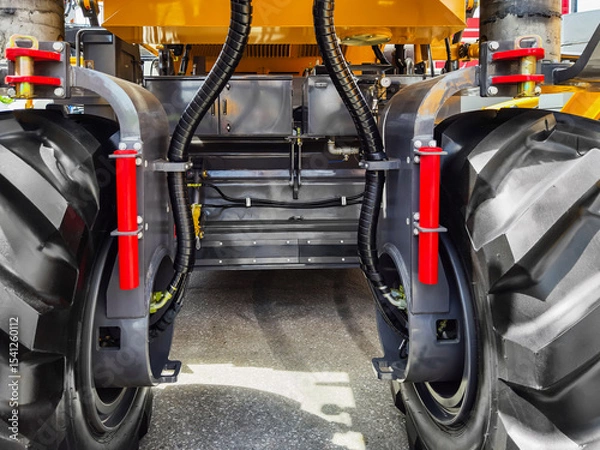 Obraz Close-up view of heavy machinery tires and hydraulic systems on a construction vehicle at a worksite