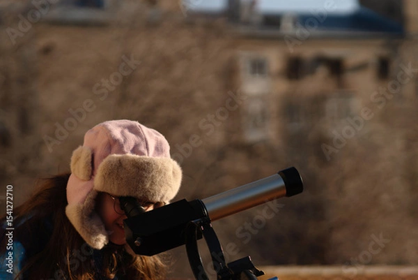 Fototapeta Girl in colorful jacket points while preparing solar telescope observation. Education, teaching, learning concept