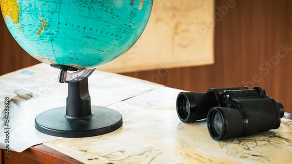 Fototapeta Binoculars on a conservationist's desk with a blurred globe next to it, the concept of wildlife conservation or conservation of an area from encroachment.