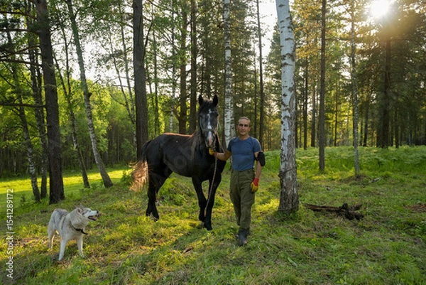 Obraz rustic man with  horse in rural village near  forest.  horse farm is surrounded by nature, hay is stacked nearby,  peaceful and traditional.  man is caring for  horse
