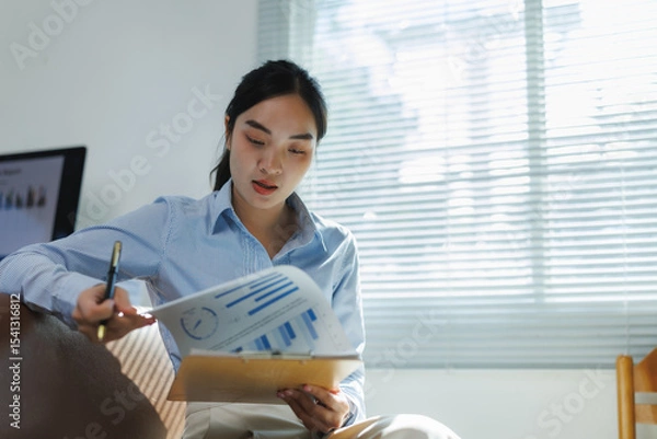 Fototapeta Businesswoman analyzing charts and graphs in modern office