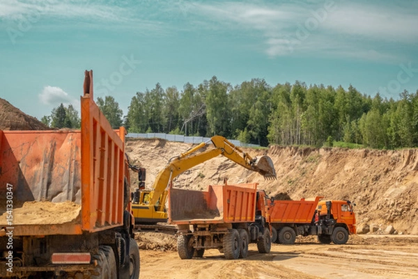 Fototapeta The process of loading sand in a sand quarry. Trucks are waiting for cargo.