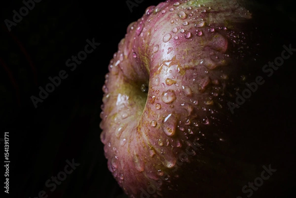 Obraz A high-resolution macro photo of a fresh apple with water droplets clinging to its skin, set against a black background. The lighting enhances the texture and freshness of the fruit