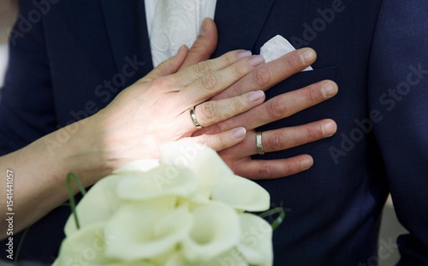 Obraz Close up of hands of bride and groom with rings and flowers