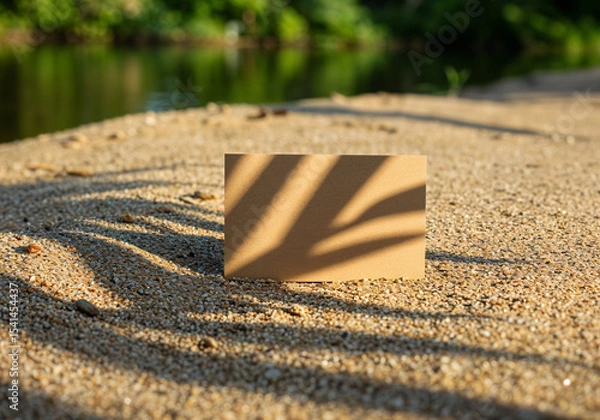 Fototapeta Kraft paper card with palm leaf shadows on sandy beach surface