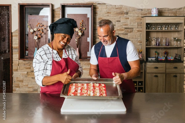 Fototapeta Chefs showing tray of uncooked appetizers making thumbs up sign during cooking course