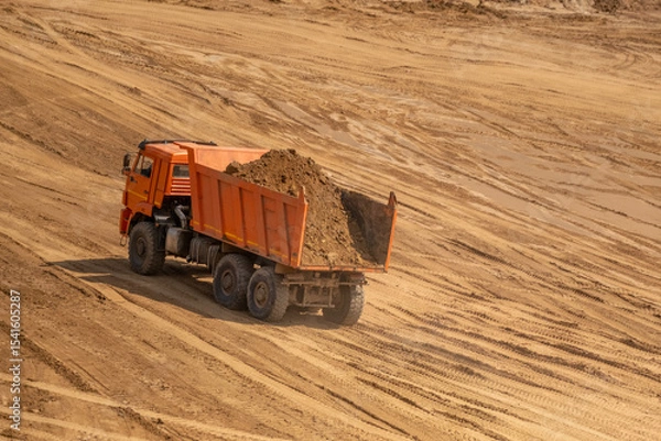 Fototapeta A loaded car drives out of a sand quarry. Sunny weather and clear skies