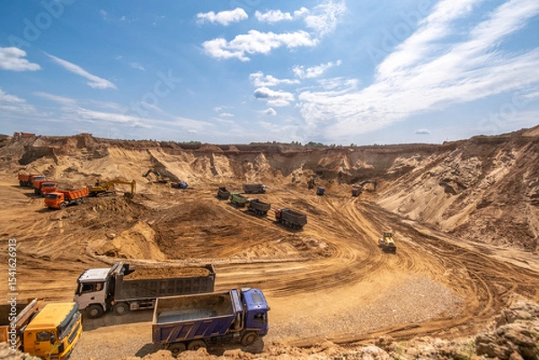 Fototapeta From afar - the work of a sand quarry. There is a lot of equipment, the development of minerals is underway.