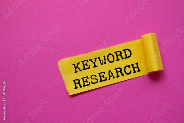 Obraz Keyword research message written on ripped torn yellow paper piece on pink background. Conceptual keyword research symbol. Copy space.