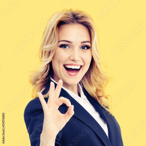 Fototapeta Portrait image - happy smile blond hair businesswoman business woman in blue formal suit jacket, pointing ok okay positive hand sign gesture, isolated yellow color background. Square