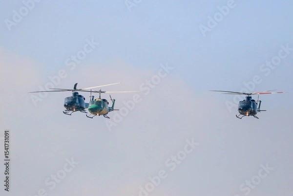Obraz bell 212 rescue helicopter in camouflage colours and  black bell 412 helicopters are flying formation with national flag of sri lanka