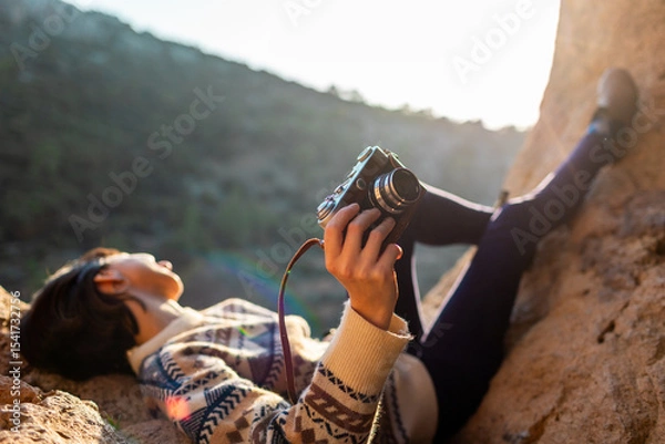 Fototapeta happy woman in the mountains with a camera in her hands. girl relaxing and taking photos in the mountains. trekking and hiking. girl with a camera.