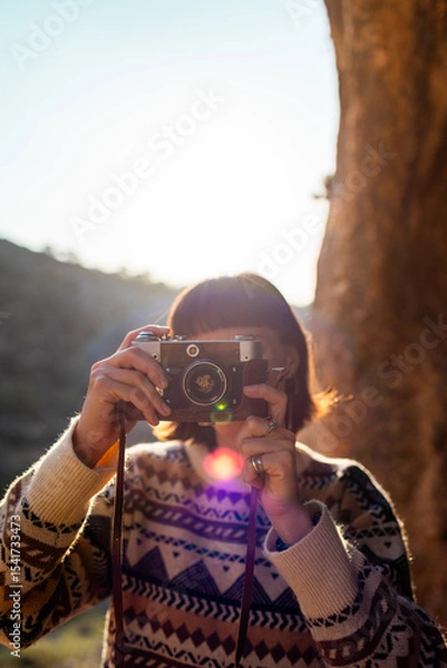 Fototapeta happy woman in the mountains with a camera in her hands enjoying the moment. trekking and hiking. girl with a camera.