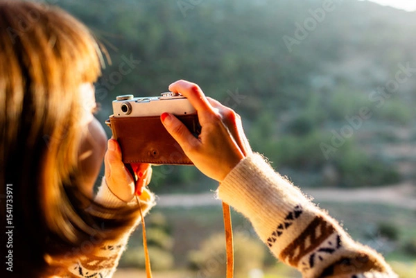 Fototapeta happy woman in the mountains with a camera in her hands. girl relaxing and taking photos in the mountains. trekking and hiking. girl with a camera.