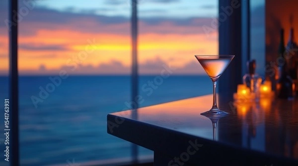 Fototapeta A sleek martini glass on a glossy bar counter, with a breathtaking ocean sunset visible through floor-to-ceiling windows in the background.
