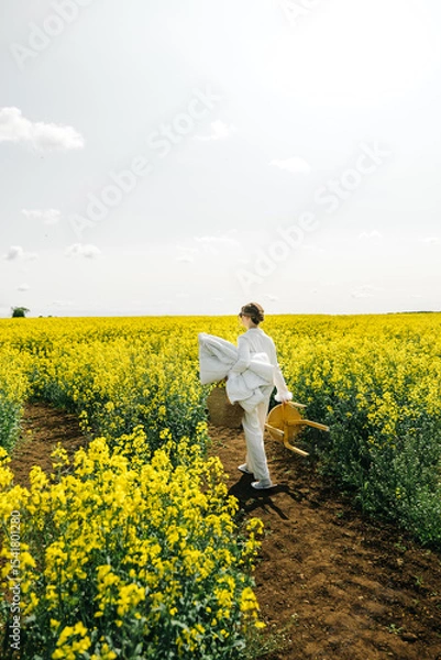 Fototapeta Walking through bright yellow flowers in a vast field on a sunny day