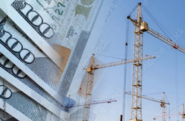Fototapeta Construction cranes on a background of money. Сoncept of rising and changing construction costs