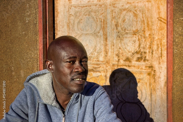 Fototapeta village single african man sited in front of the house in the yard, sunny day