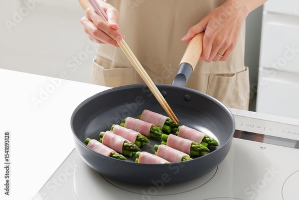 Fototapeta フライパンでアスパラベーコンを焼く料理のシーン　Asparagus Bacon Being Cooked in a Frying Pan