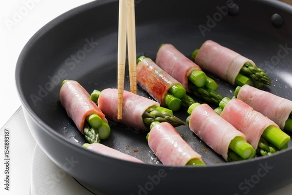 Fototapeta フライパンでアスパラベーコンを焼く料理のシーン　Asparagus Bacon Being Cooked in a Frying Pan