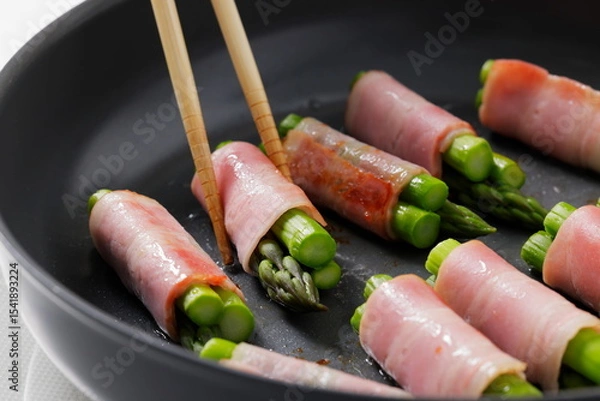 Fototapeta フライパンでアスパラベーコンを焼く料理のシーン　Asparagus Bacon Being Cooked in a Frying Pan