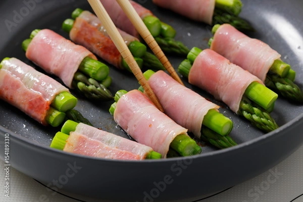 Fototapeta フライパンでアスパラベーコンを焼く料理のシーン　Asparagus Bacon Being Cooked in a Frying Pan