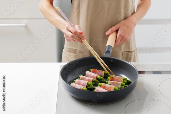 Fototapeta フライパンでアスパラベーコンを焼く料理のシーン　Asparagus Bacon Being Cooked in a Frying Pan