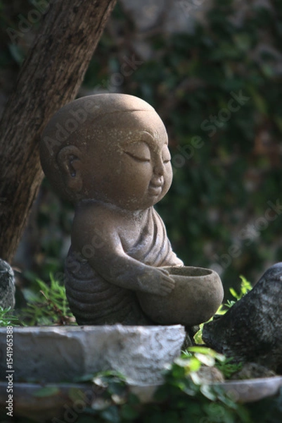 Fototapeta Serene Contemplation: An adorable statue of a small monk meditates in tranquil garden, conveying inner peace. 