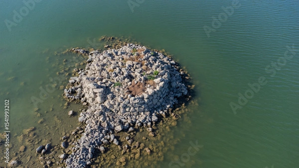 Fototapeta Ancient nuraghe ruins partially submerged in a Sardinian lake, exposed by low water