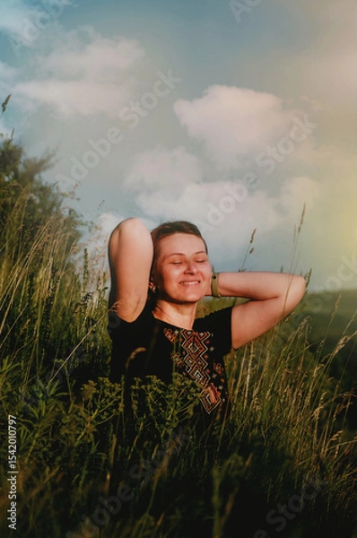 Fototapeta Happy girl with closed eyes and smile in mountains in embroidered shirt