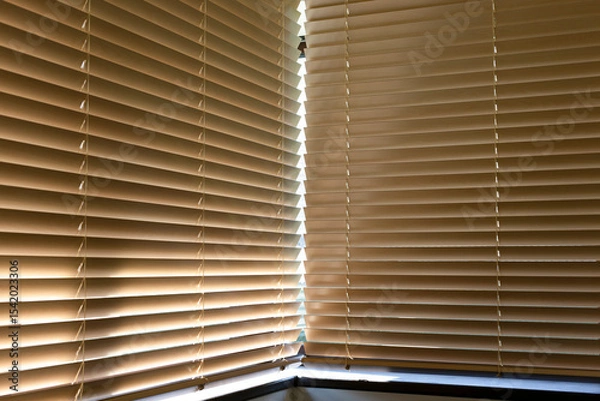 Obraz Motorized wood blinds cover two adjacent windows, filtering sunlight with ease. Made from natural materials, these automated slats provide light control, privacy, and a warm, modern interior touch.