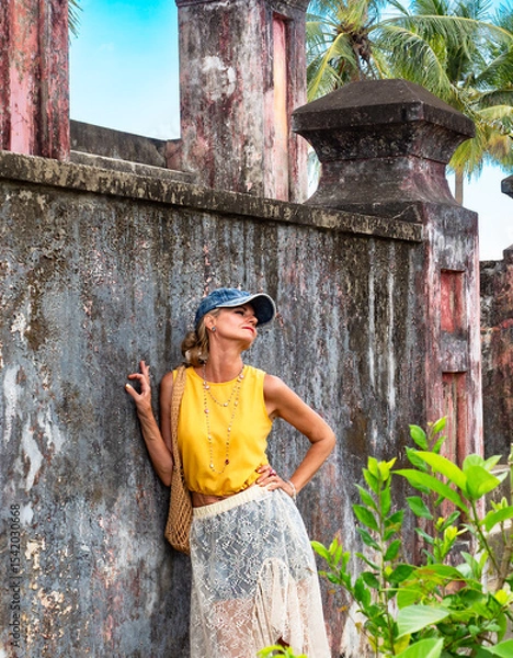 Fototapeta A woman posing near a wall of ancient ruins in Nha Trang, Vietnam - a moment of silence amidst the historical heritage and nature of Southeast Asia. Tourism concept