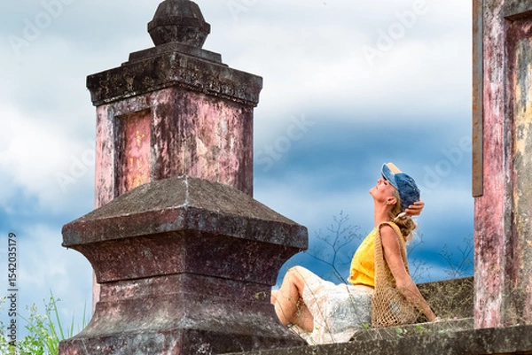 Fototapeta A woman sits on ancient ruins in Nha Trang, Vietnam - a moment of silence amidst the historical heritage and nature of Southeast Asia. Tourism concept