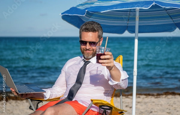 Obraz Travel and business. Man freelance work online at sea beach. Businessman working at sea summer vacation. Online freelance. Businessman remote worker with laptop. Business man using laptop in beach