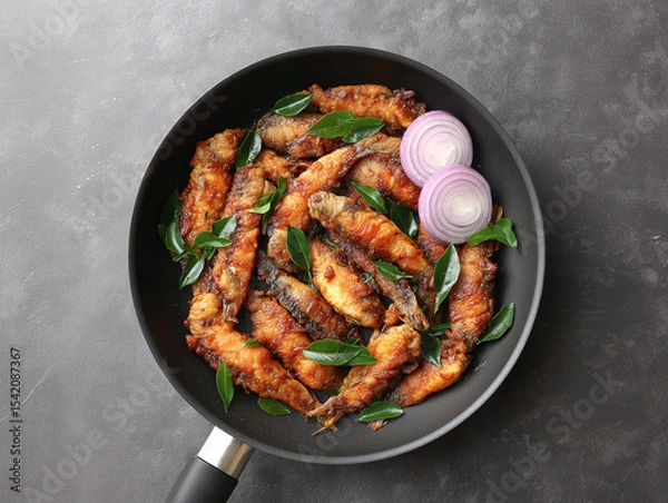 Fototapeta Savory Fried Fish Dish: This image showcases a tantalizing dish of fried fish, artfully arranged in a sleek pan, garnished with aromatic herbs and sliced onions.