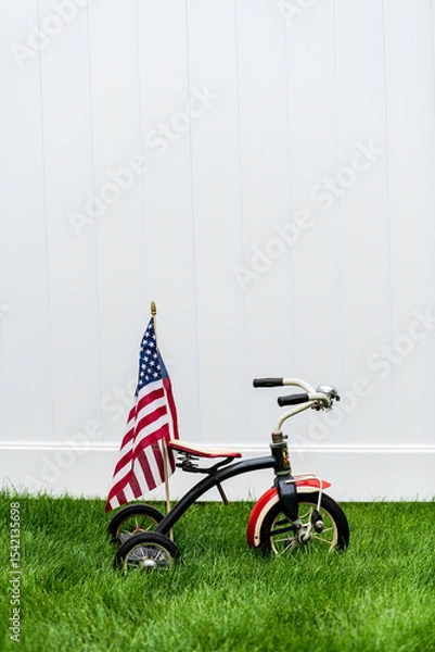 Obraz vintage tricycle with American flag on green grass with vertical white background and room for copy