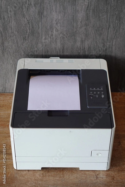 Fototapeta This front-facing shot of printer with a single sheet of paper outing from its top output tray.