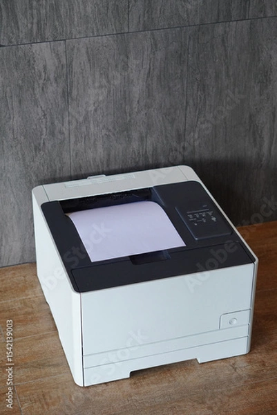Fototapeta top view laser printer resting on a wooden floor, grey tile wall background, decor, technology, fashion, business, copy space