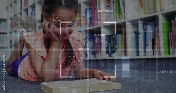 Obraz Reading girl lying on carpeted library floor, focusing on open book with digital overlay