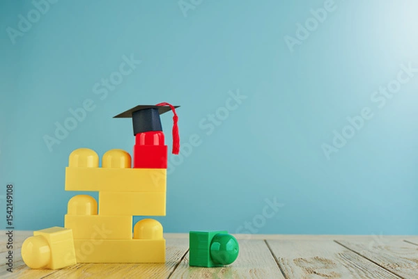 Obraz Multicolored construction cubes for children and black and masters cap or an oxford cap on blue background. Concept education, development and learning. Empty background. Back to school concept.