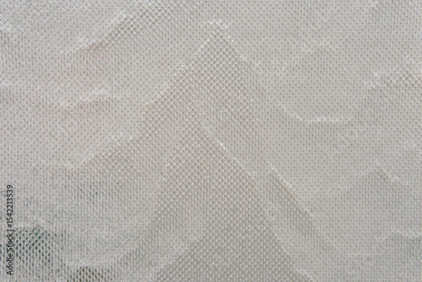 Fototapeta Water streams down glass covered with metal mesh, catching light and texture. The effect is cool, modern, and quietly captivating.