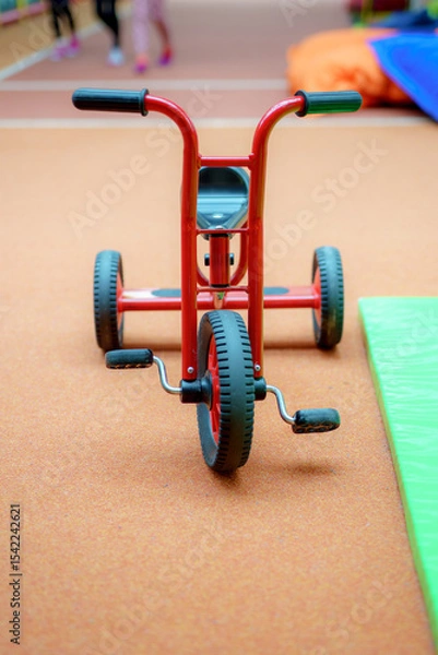 Obraz Bright red tricycle sits on a gym floor during an active children's play session in the community center