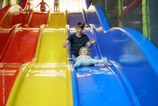 Obraz Children enjoy vibrant slides in a play area during a sunny afternoon, creating joyful memories and laughter