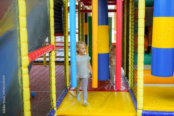 Fototapeta Children enjoying an indoor play area filled with colorful structures and climbing frames in a recreational center