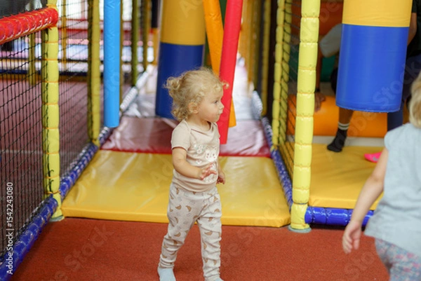 Obraz Toddler exploring colorful indoor play area filled with soft obstacles and interactive activities in the afternoon