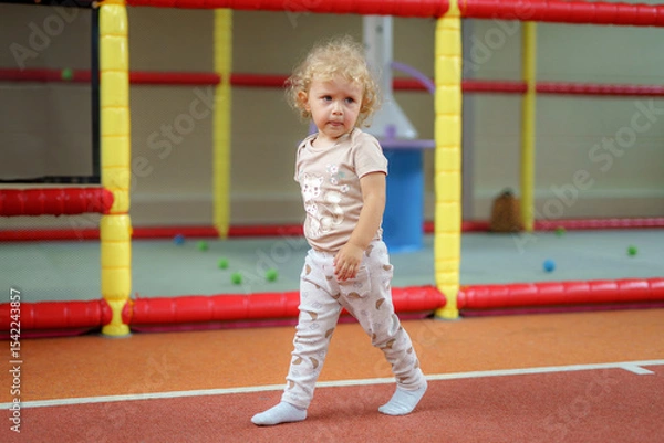 Fototapeta Child walking on a colorful indoor playground with soft play equipment in a fun and safe environment